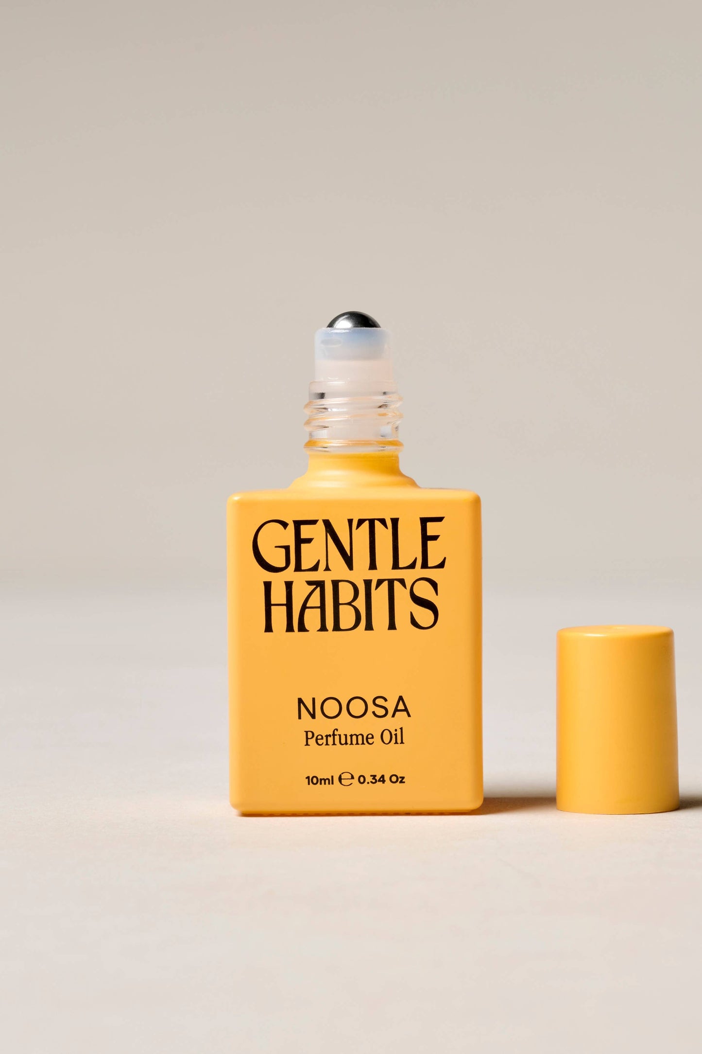 Yellow bottle of Gentle Habits Noosa perfume oil on a beige background