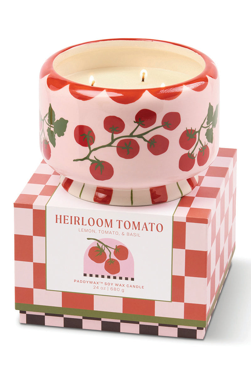 Candle in a decorative container with 'Heirloom Tomato' packaging on a white background