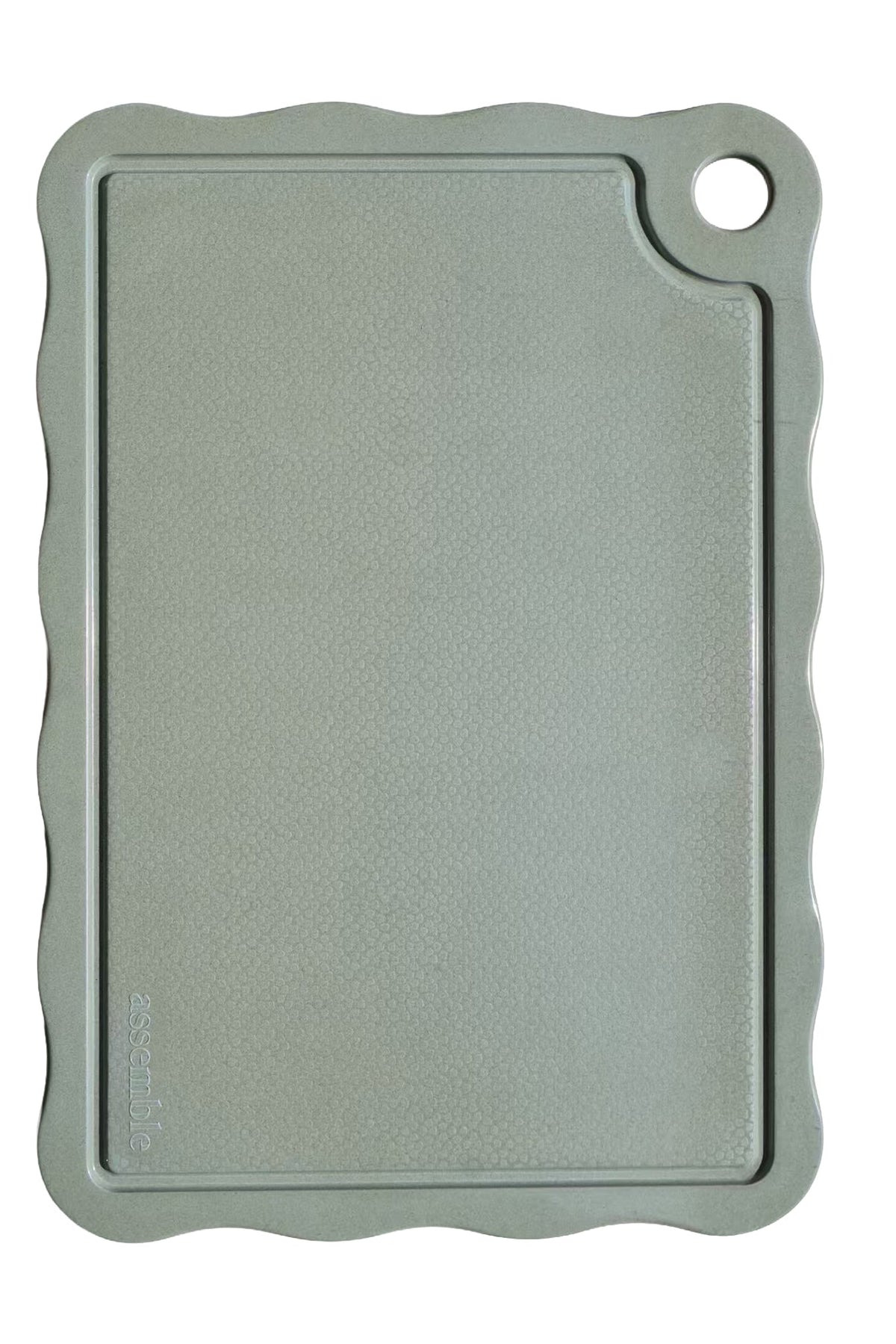 Soft green cutting board with scalloped edge on a white background