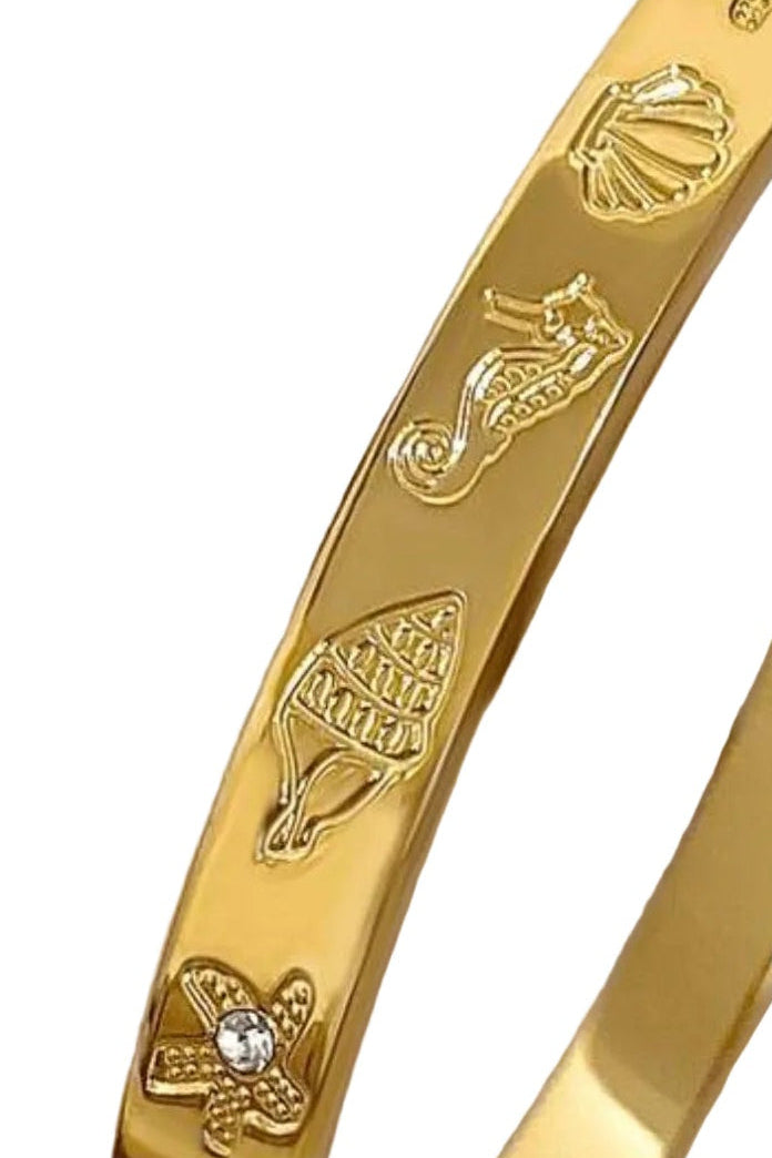 Gold bracelet with engraved designs on a white background