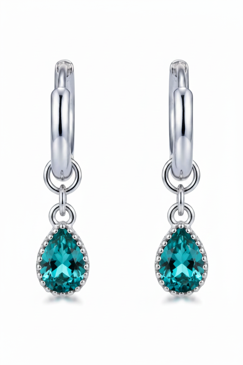 Silver earring with a blue gemstone on a beige background
