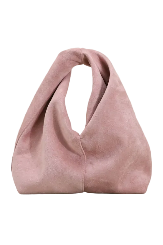 A dusty pink suede slouchy shoulder bag with a single integrated handle, set against a textured light sage green background.