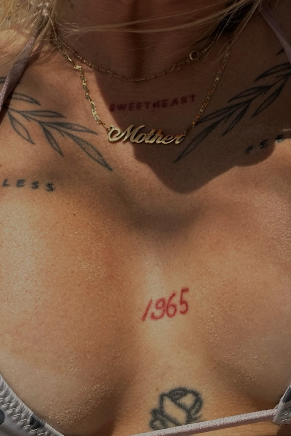 Close-up of a person's chest with tattoos and jewelry