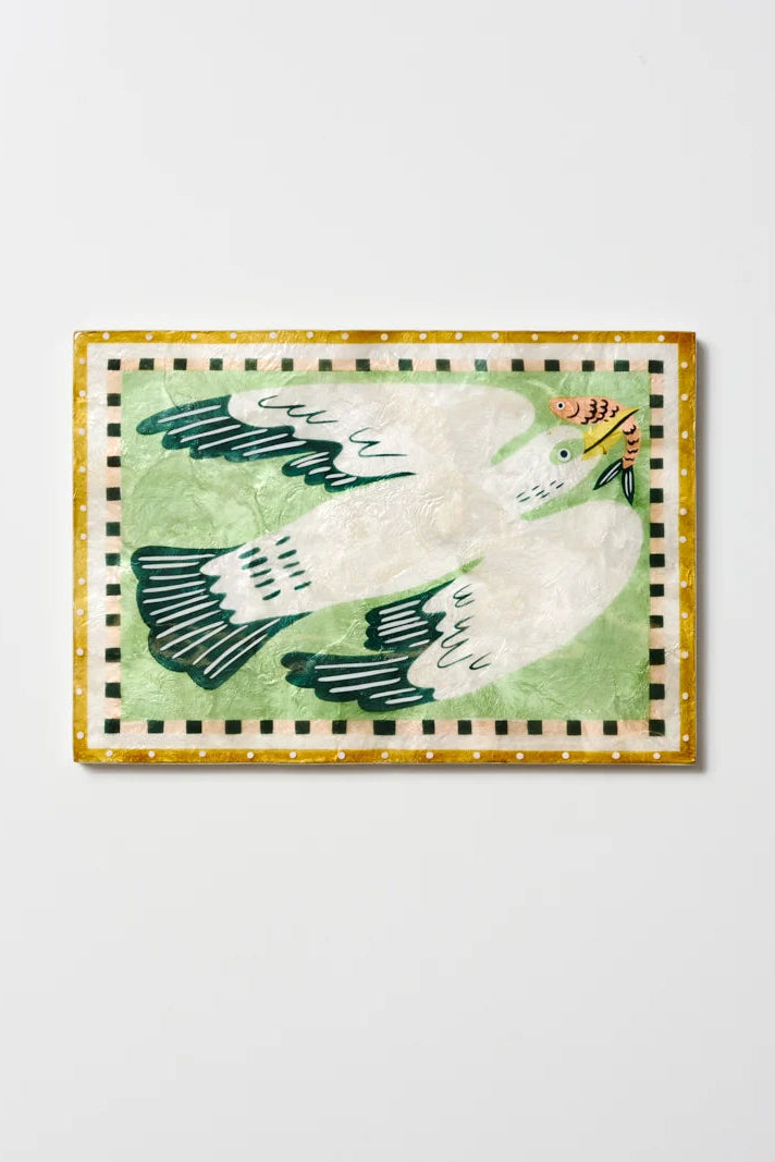A square decorative art print or tile featuring a stylized white dove with dark green wings on a light green background, bordered by a gold and black checkered frame, shown against a plain light gray wall.