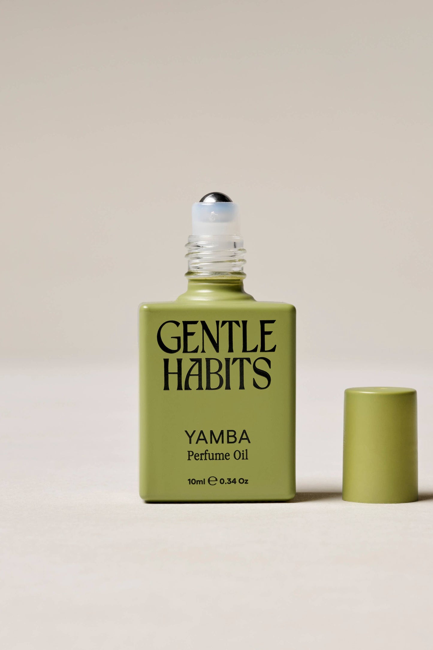 Green bottle of 'Yamba' perfume oil by 'Gentle Habits' on a beige background