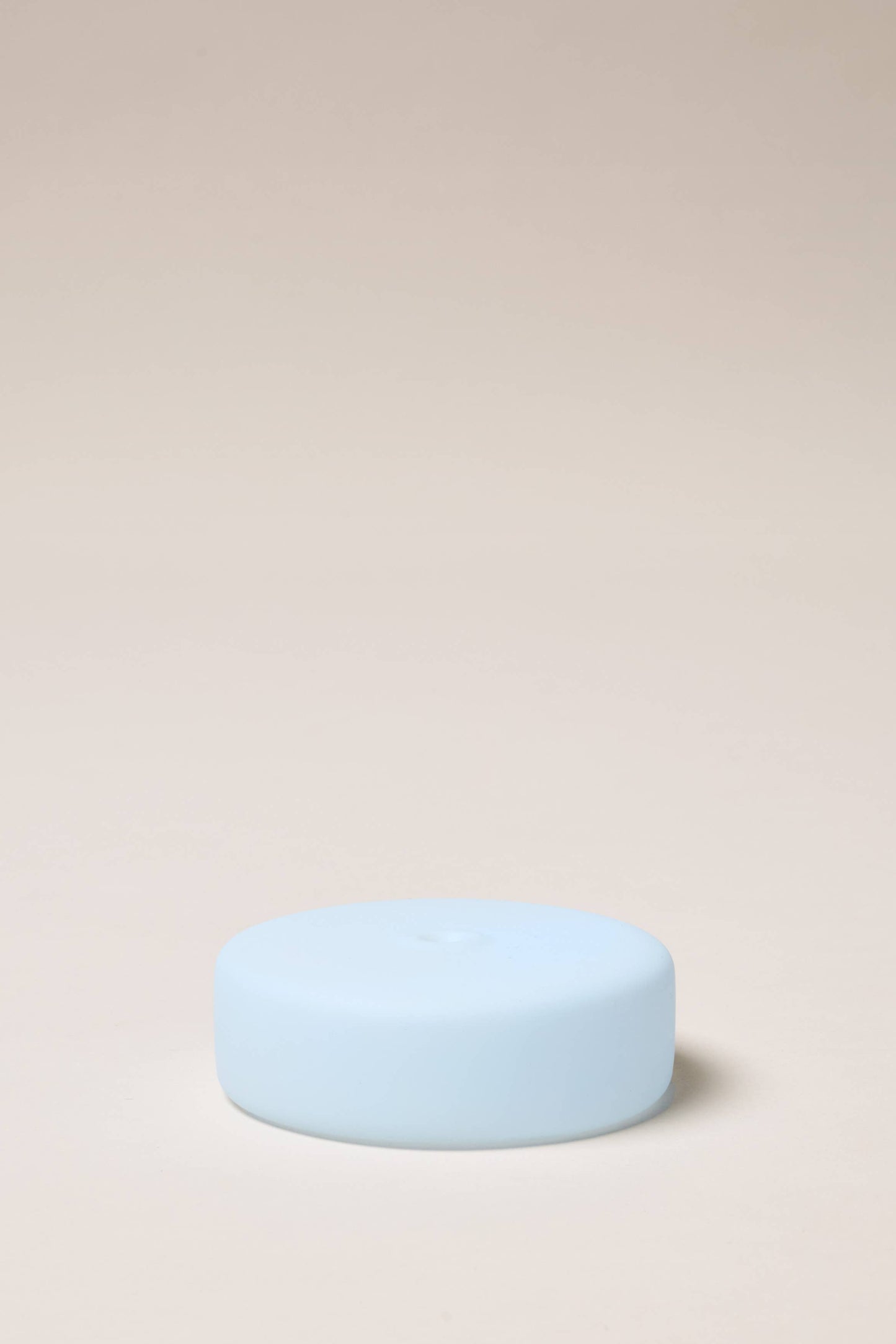 Light blue cylindrical object on a beige background