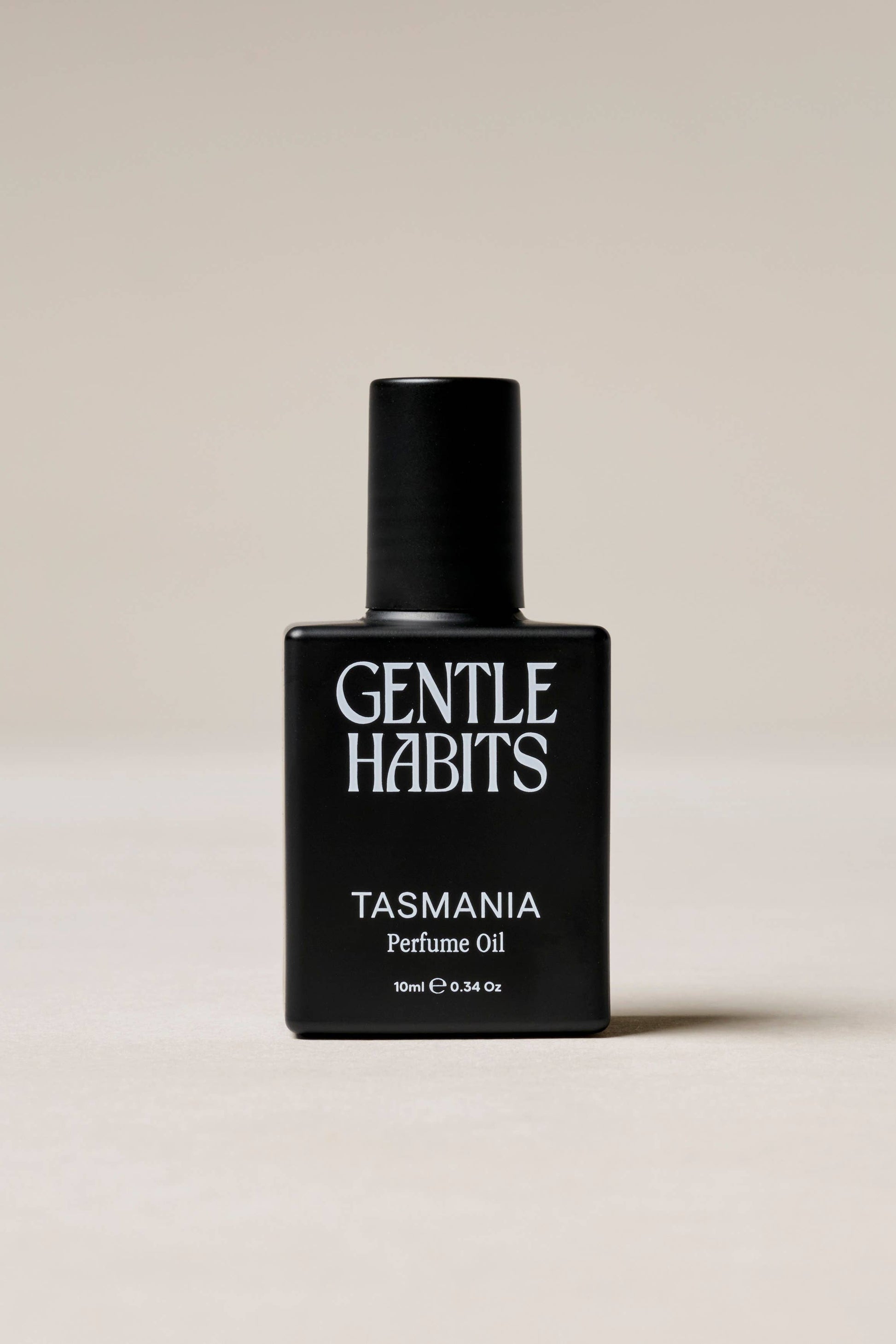 Black perfume bottle labeled 'Gentle Habits Tasmania' on a beige background