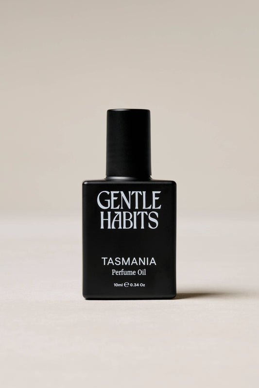 Black perfume bottle labeled 'Gentle Habits Tasmania' on a beige background