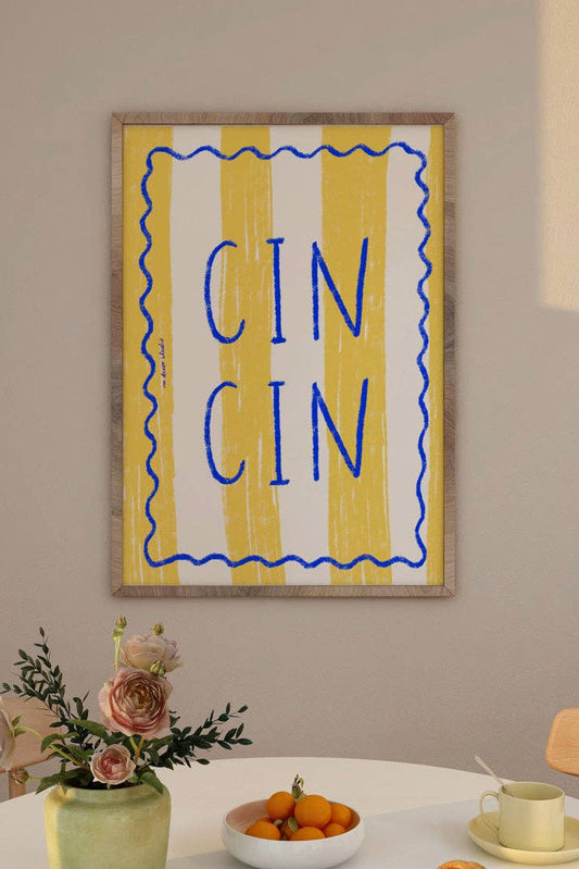 Framed artwork with 'CIN CIN' text above a dining table with a vase, fruit bowl, and bread.