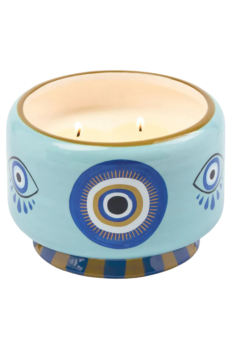 Decorative candle in a blue holder with eye designs on a white background
