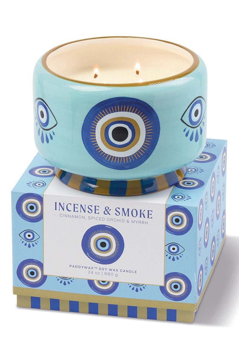 Candle with decorative packaging featuring eye designs on a white background
