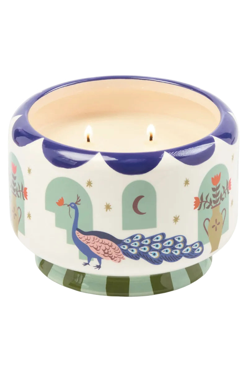 Decorative candle with peacock design on a white background