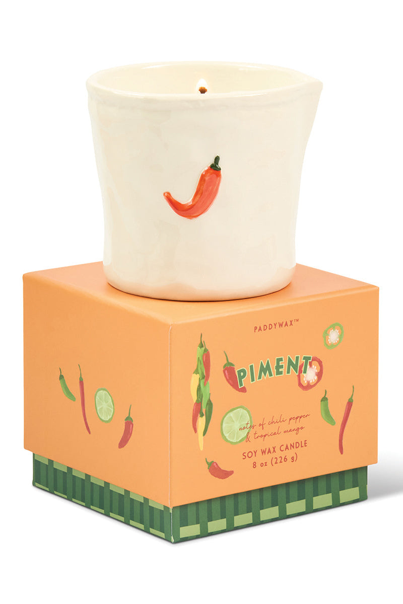 Candle with chili pepper design on a matching box against a white background