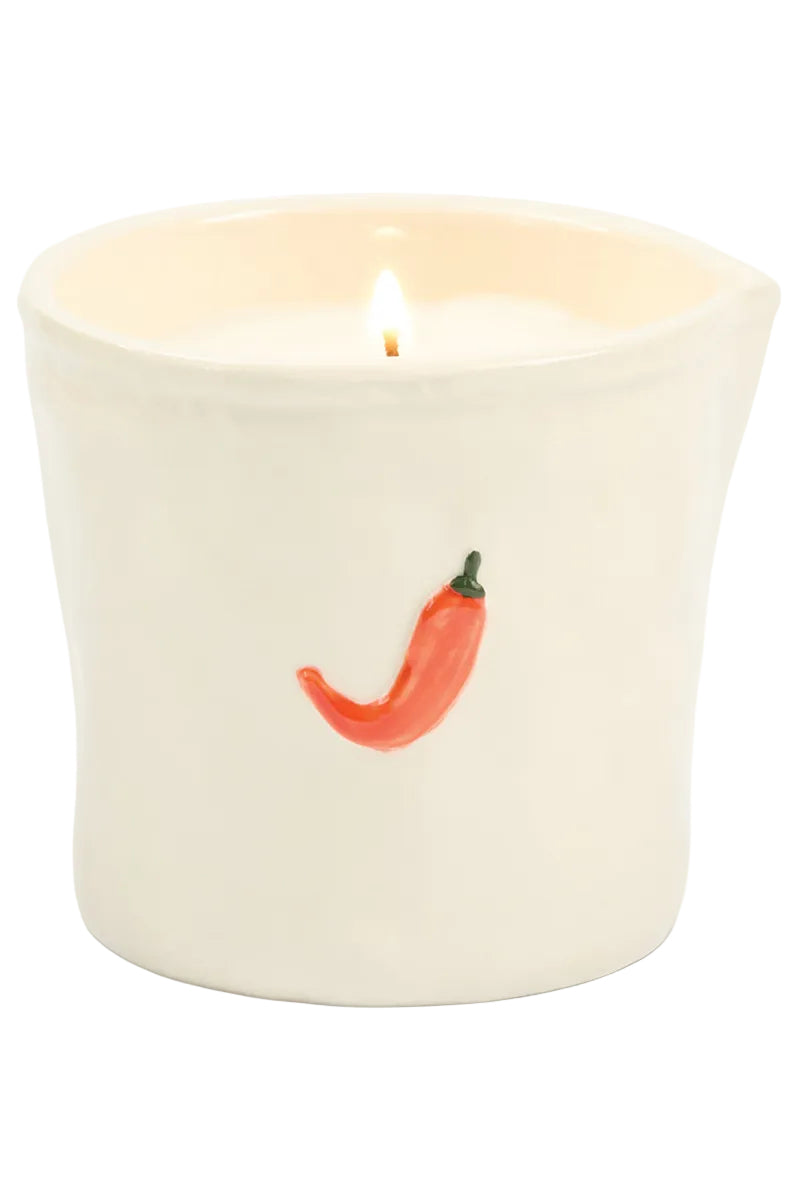Candle in a white container with a red chili pepper design on a white background