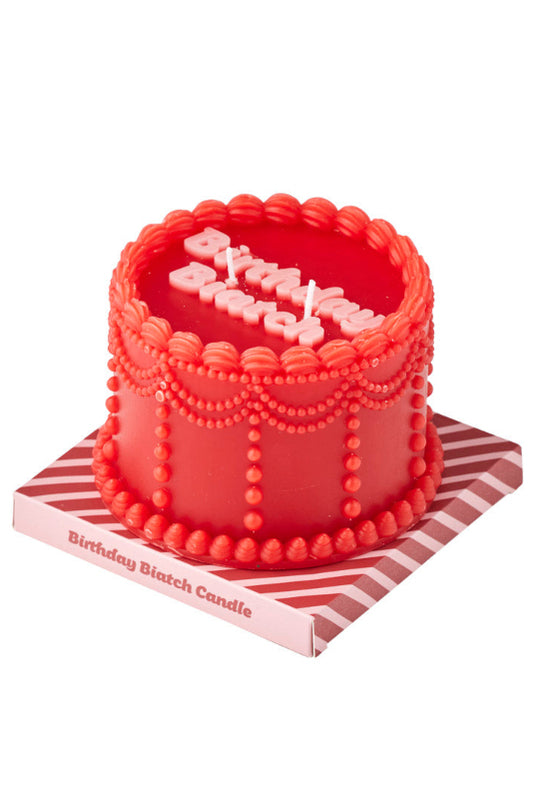 A red birthday candle shaped like a decorated cake, with white candle letters spelling 'Birthday' on top and a pink-and-white striped base, shown on a white background.