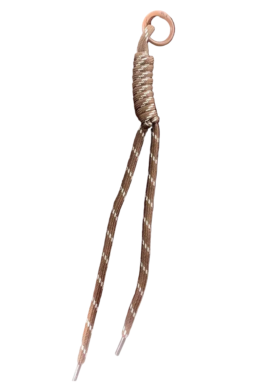 A close-up of a brown and beige braided cord with a metal ring and wrapped connector, resting on a dark wooden tray.