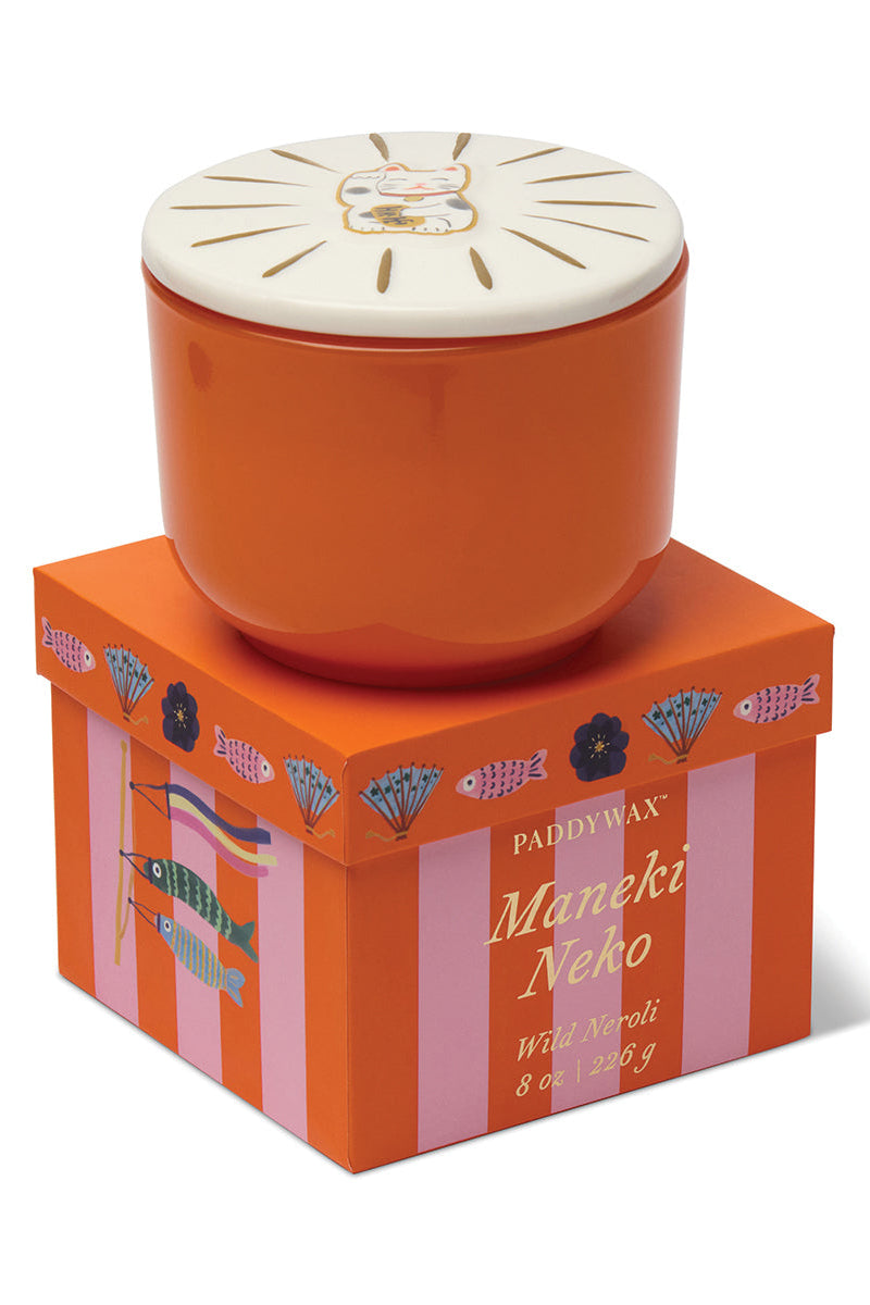 Candle in an orange box with 'Maneki Neko' design on a white background