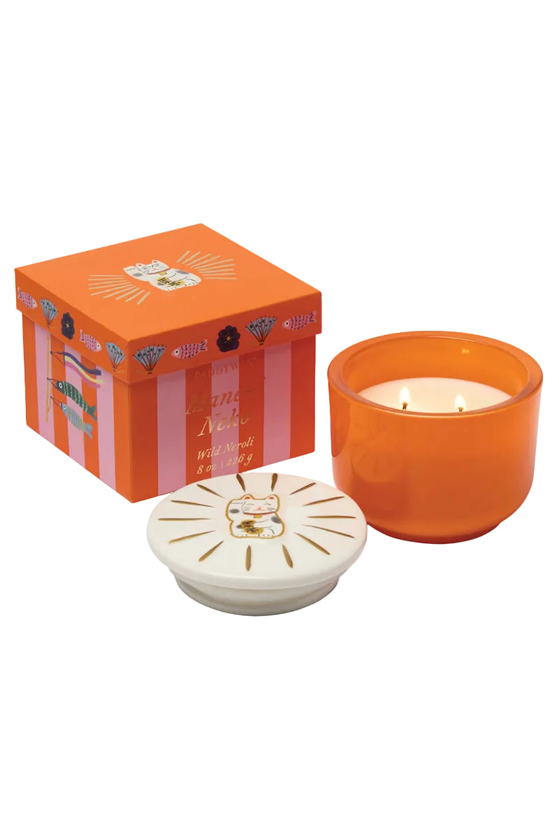 Orange candle with decorative lid and matching box on a white background