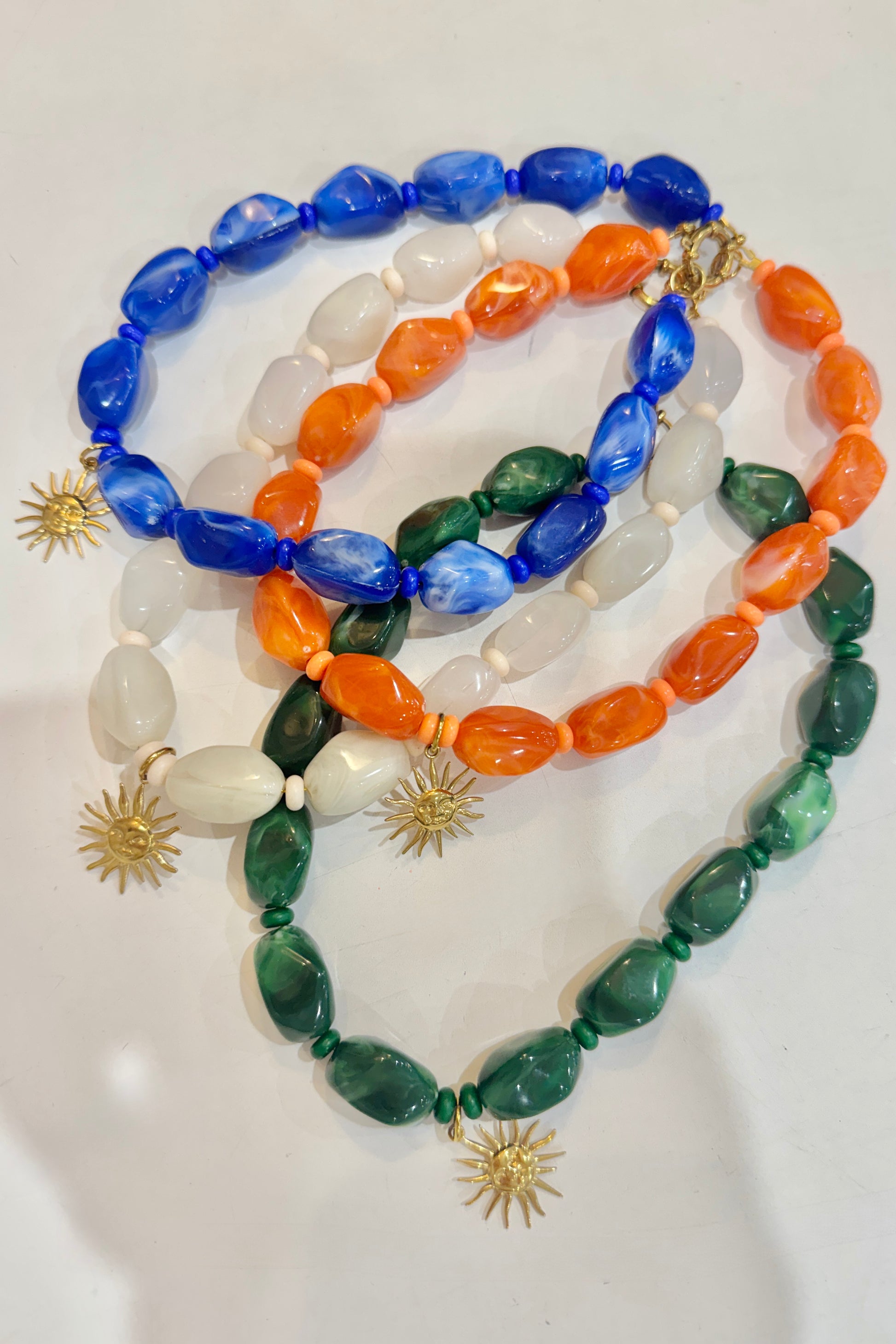 Four colourful beaded necklaces with star-shaped clasps on a white background