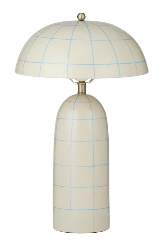 A table lamp with a tall, tapered cream-colored ceramic base and a matching dome-shaped shade, both decorated with a light blue grid pattern. The lamp features a brass-colored neck and finial, set against a plain white background.