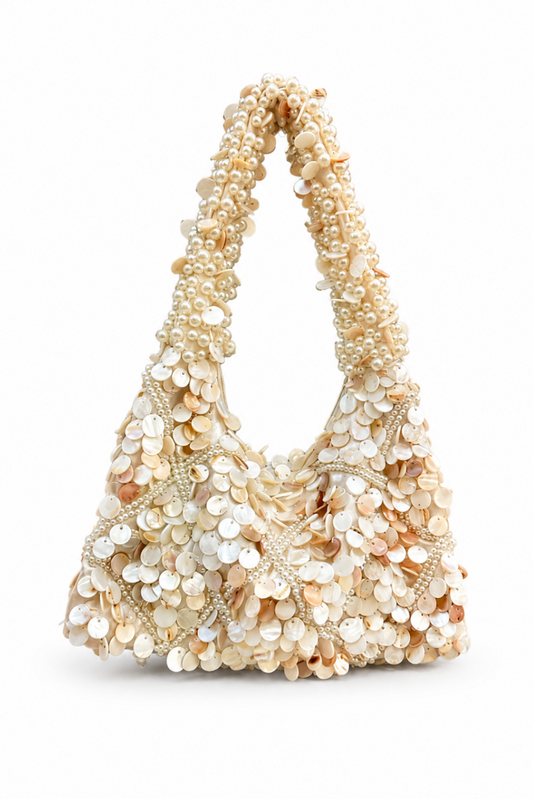 Beige handbag with pearl-like embellishments on a white background