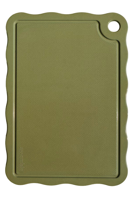 Green cutting board with scalloped edge on a white background