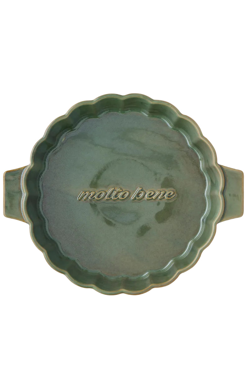 Green ceramic dish with scalloped edge and 'molto bene' text on a white background