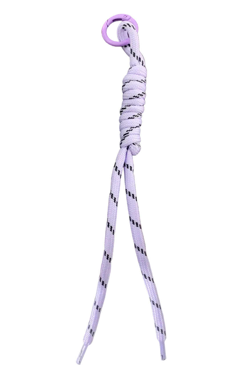 A light purple paracord keychain with a matching purple metal ring, resting on a dark brown wooden surface.