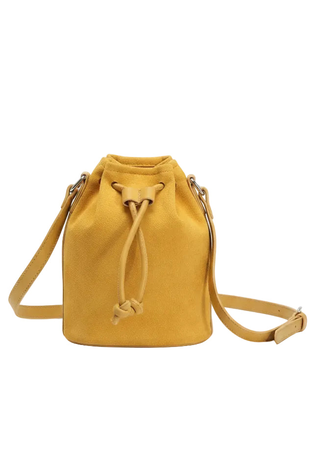 A mustard yellow suede bucket bag with a drawstring closure and a matching adjustable shoulder strap, photographed on a clean white background.