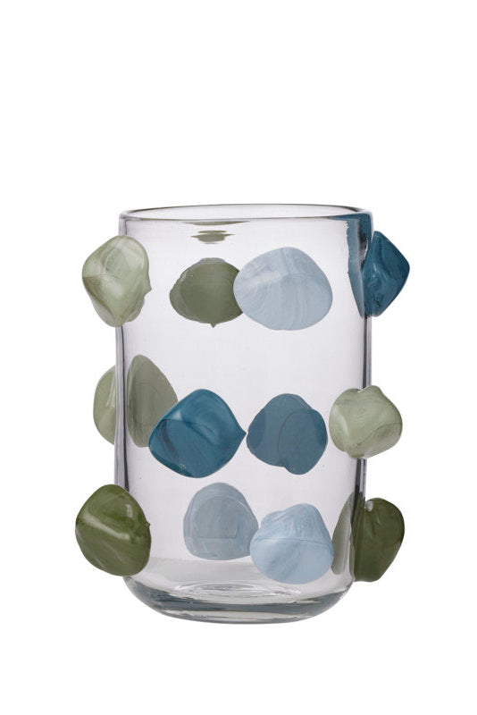A clear glass tumbler decorated with irregular, raised pebble-like shapes in muted blue, sage green, and light gray, shown against a plain white background.