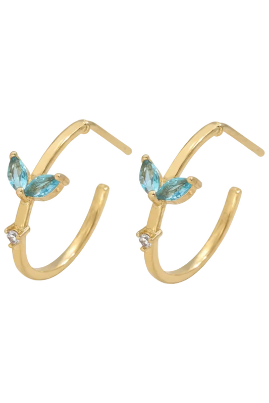 Gold hoop earrings with blue gemstones on a light background