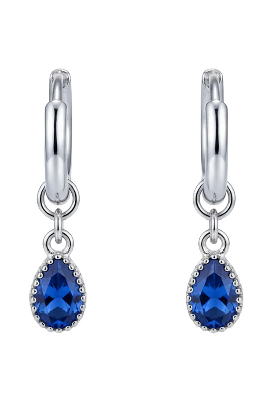 Silver earring with a blue gemstone on a beige background