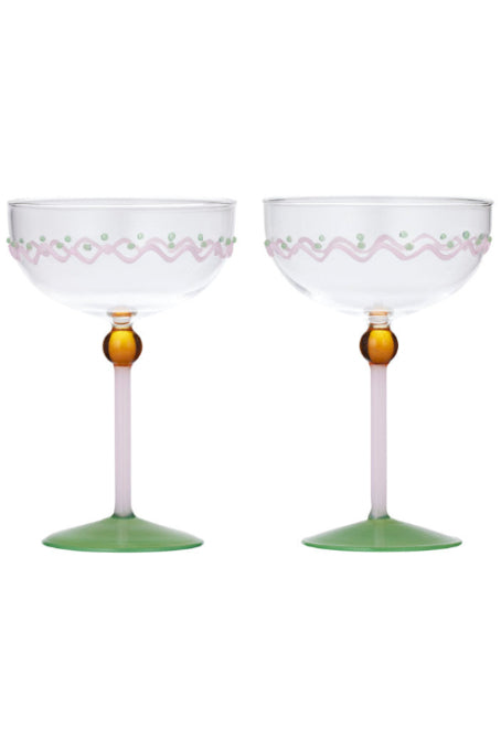 Two clear stemmed glasses with pale pink and green decorative detailing, featuring amber-colored stems and light green bases, shown on a white background.