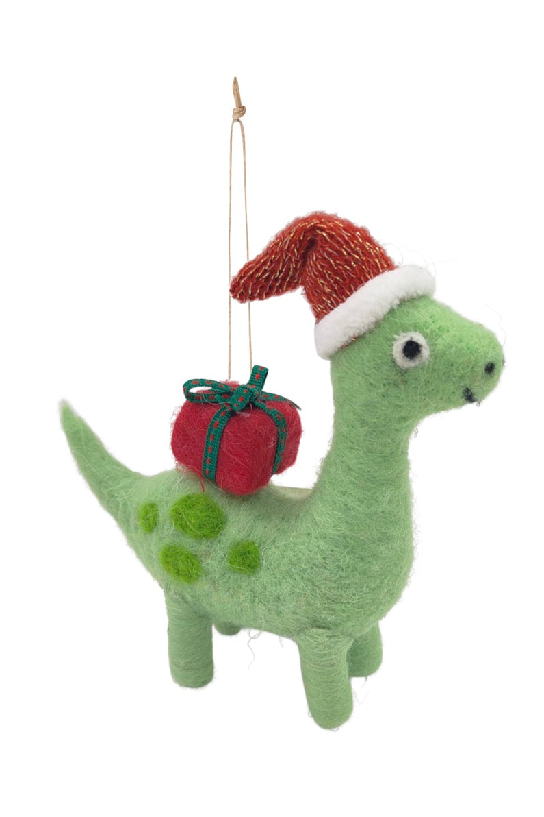 A green felt dinosaur Christmas ornament wearing a red Santa hat and carrying a small red gift bag, shown against a plain white background.