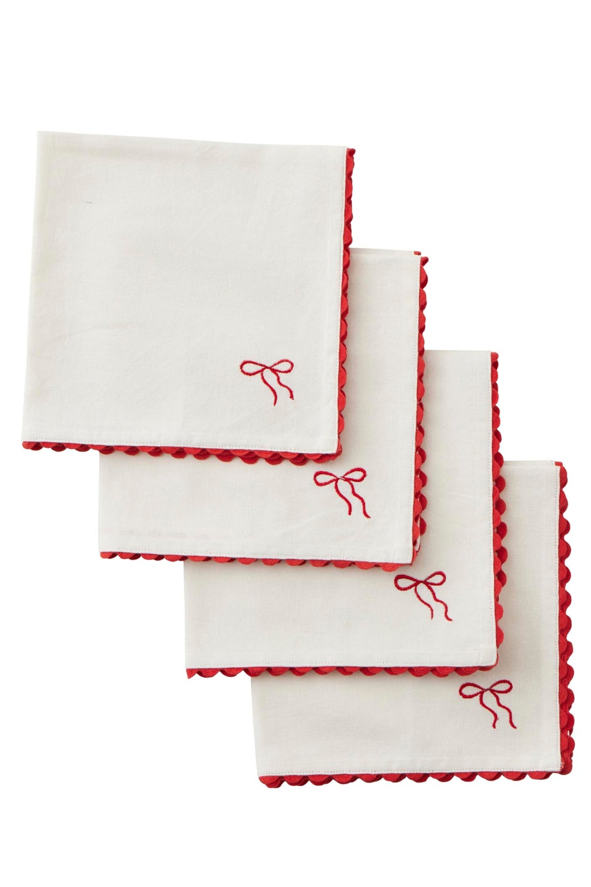 Four white square napkins with red scalloped edges and a small red embroidered bow near one corner, arranged in a staggered stack on a white background.