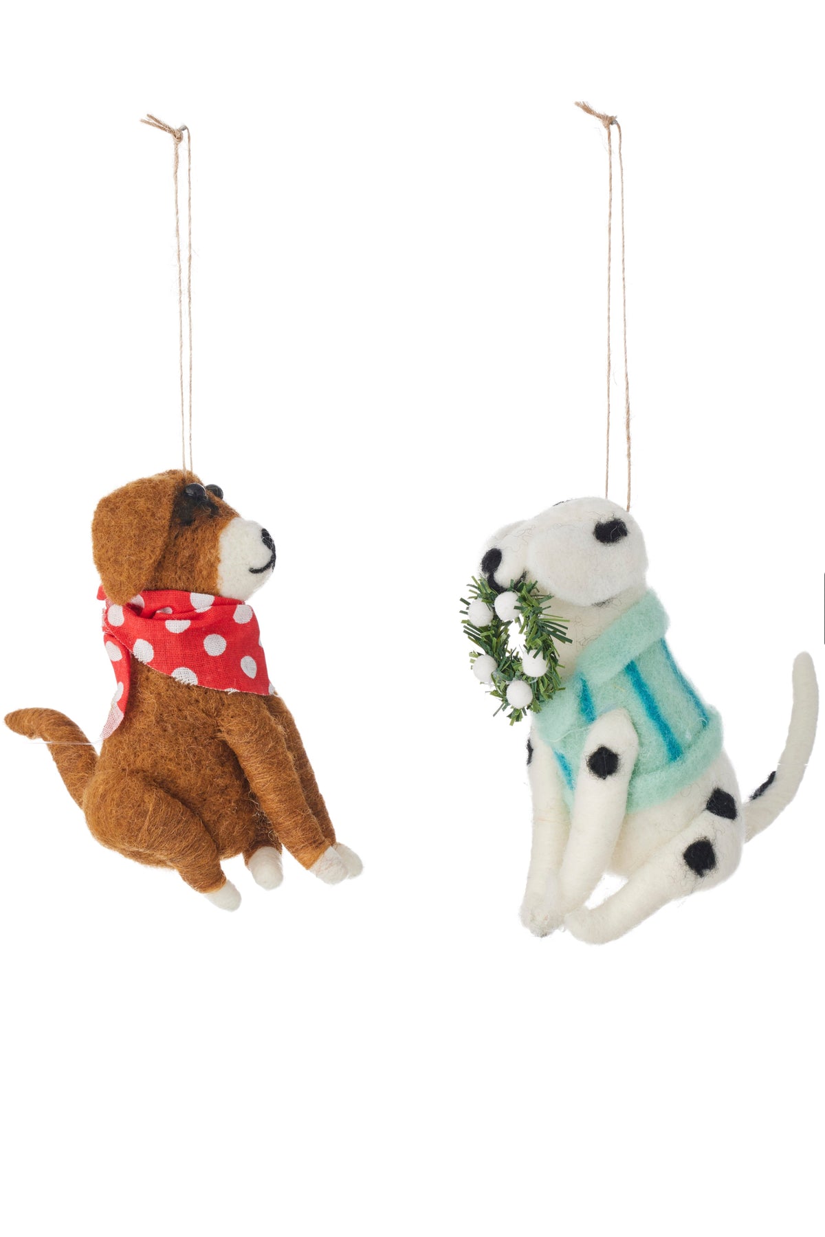 Two felt dog ornaments hanging side by side on a white background. The left ornament is brown with a red polka-dot scarf, and the right ornament is white with black spots, wearing a mint green sweater and holding a small green wreath with white flowers.