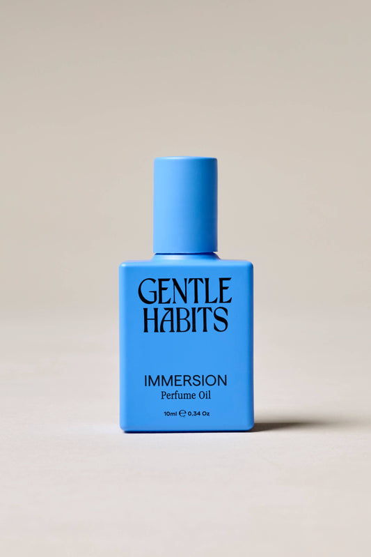 Blue bottle of Gentle Habits Immersion perfume oil on a beige background