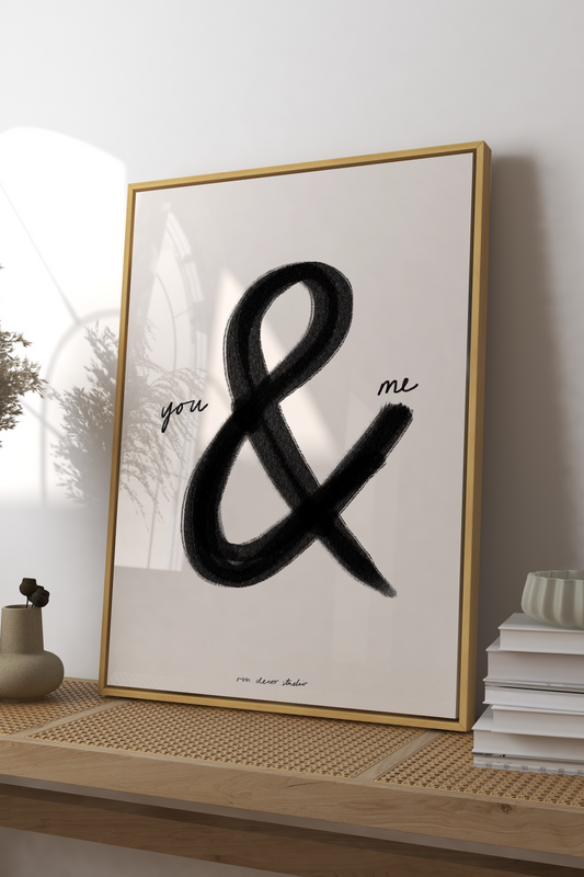 Framed artwork with a black ampersand on a wooden console table.