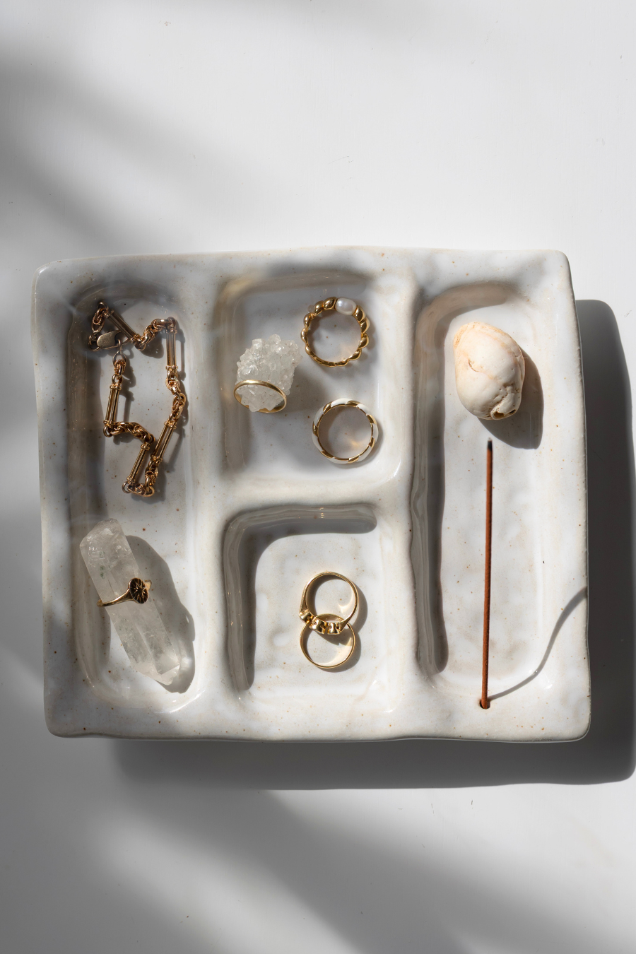 Jewelry set including rings and necklaces on a textured white surface with a soft shadow.