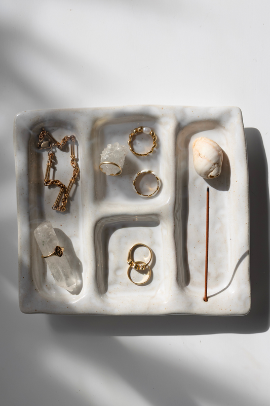 Jewelry set including rings and necklaces on a textured white surface with a soft shadow.