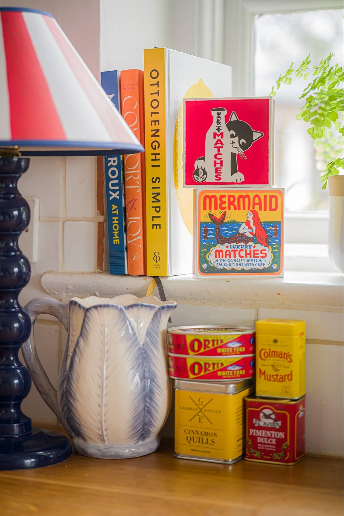 Decorative items including a striped lamp, books, and vintage matchboxes on a windowsill.