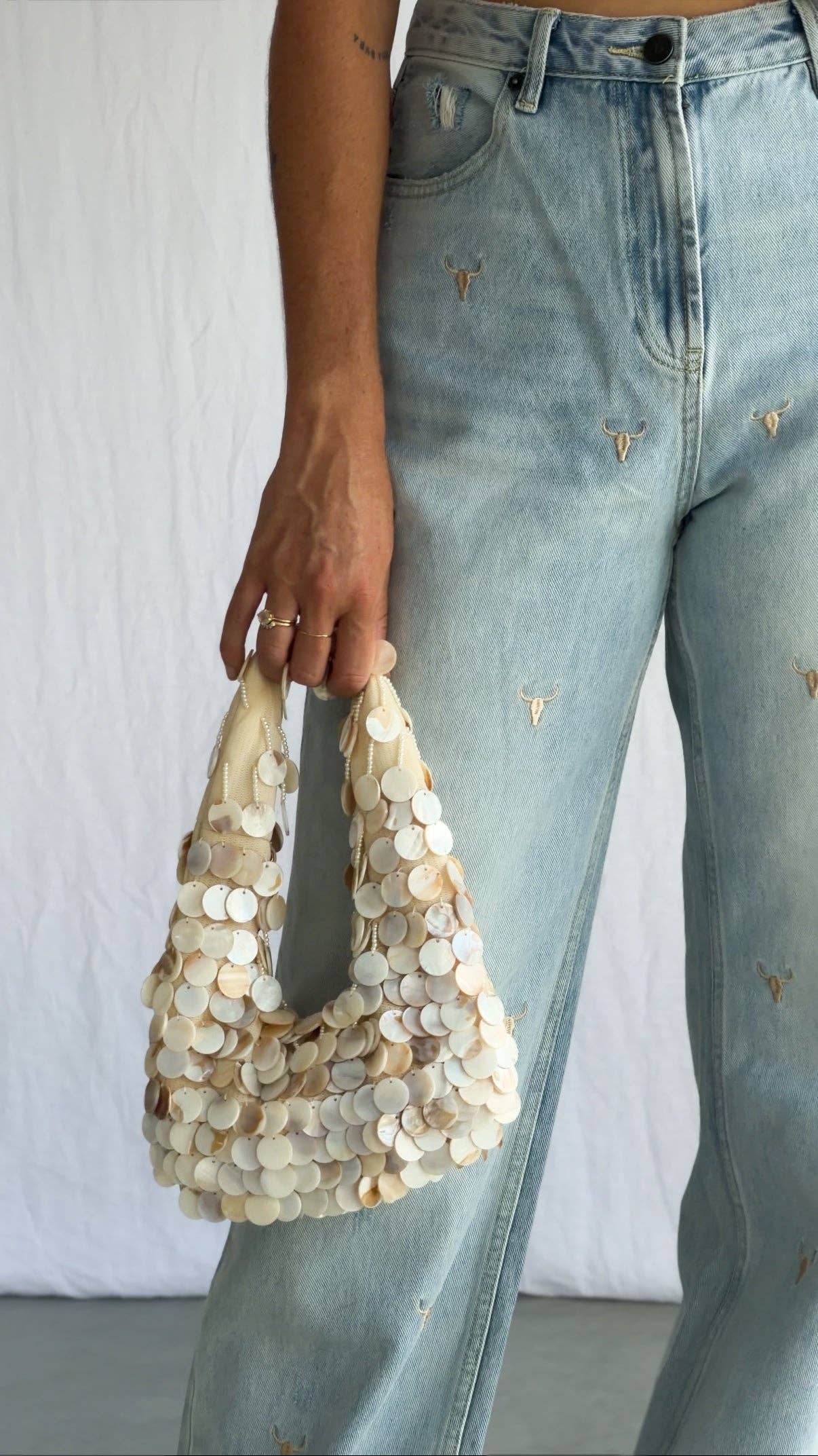Person holding a beige handbag with a plain background