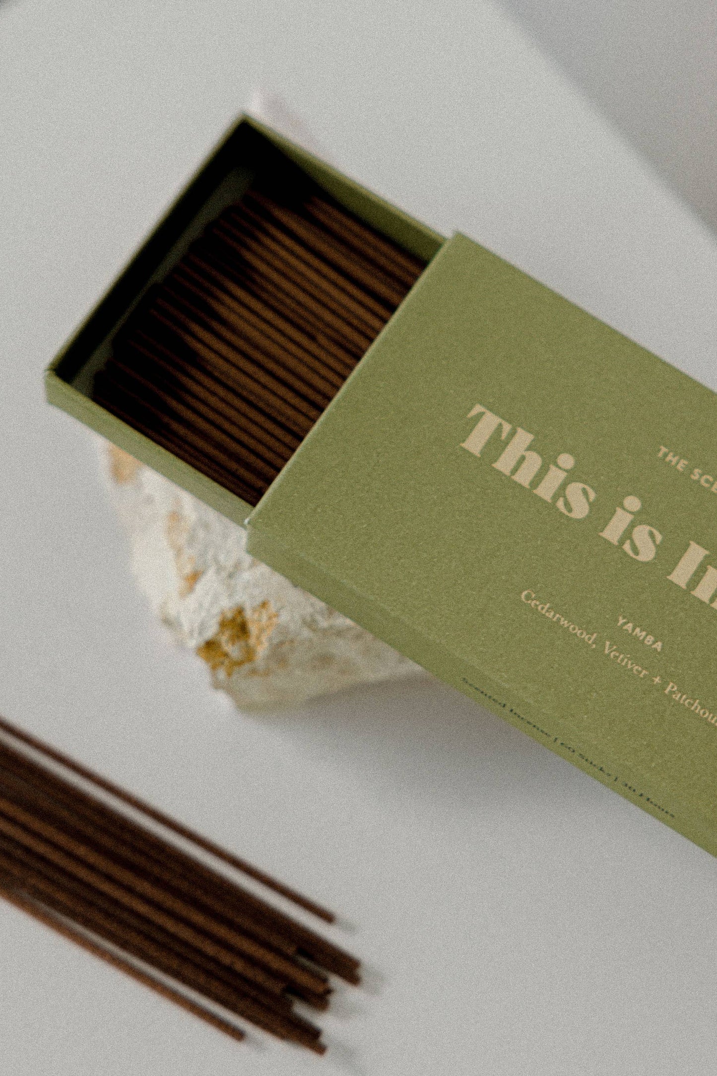 Incense sticks in an open green box with 'This is Incense' text on a light background
