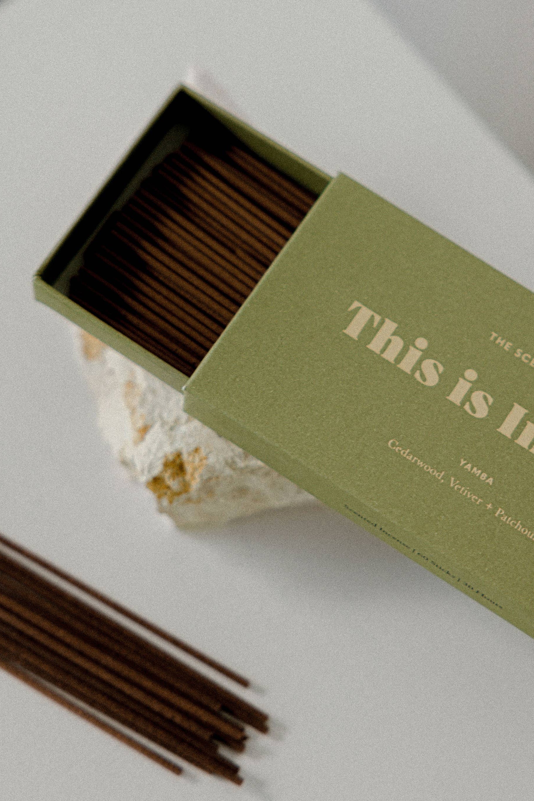 Incense sticks in an open green box with 'This is Incense' text on a light background