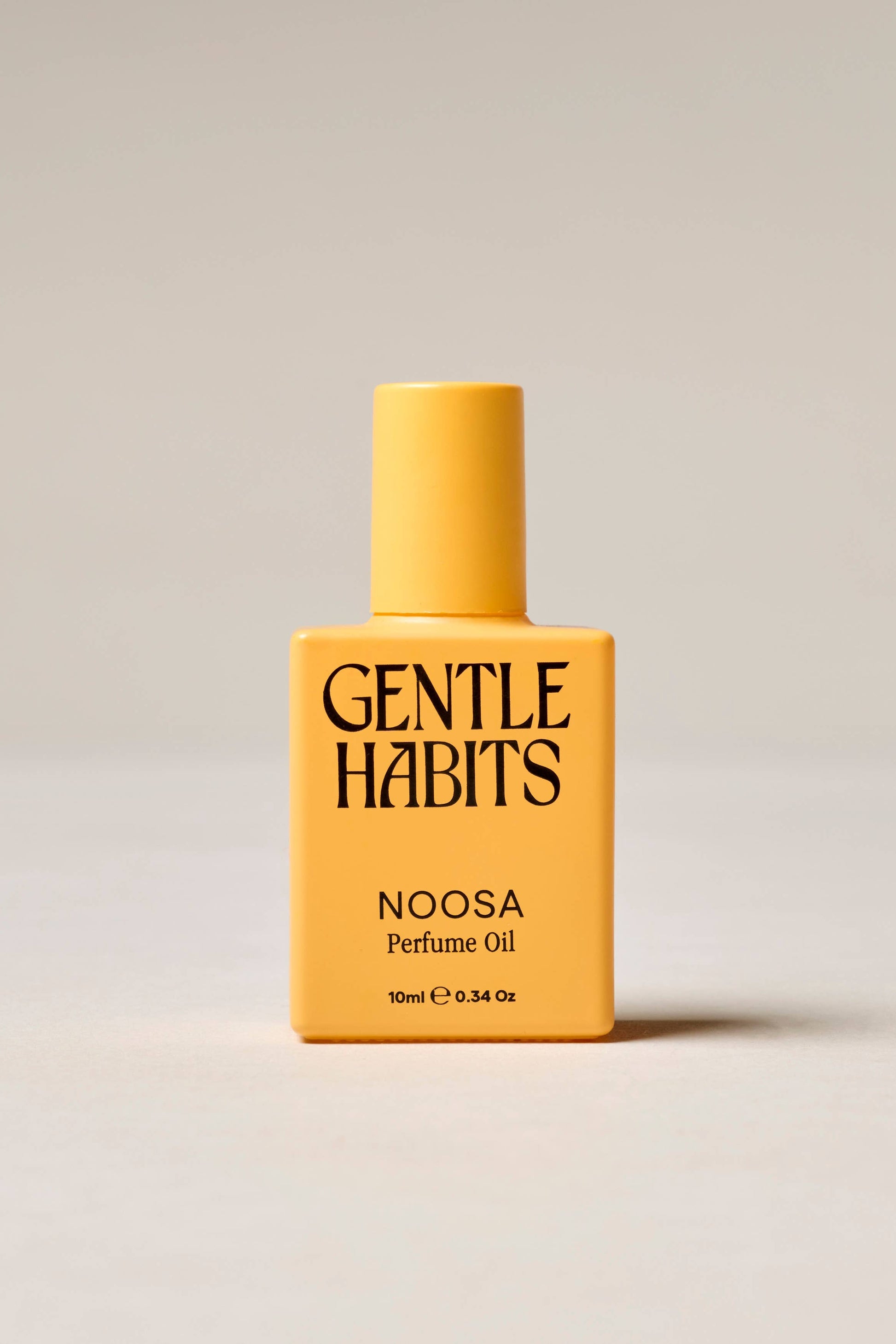 Yellow bottle of Gentle Habits Noosa perfume oil on a beige background