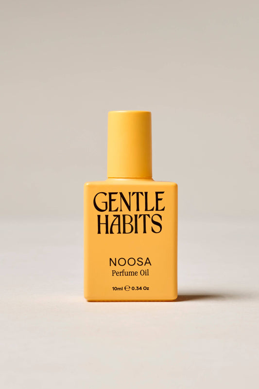 Yellow bottle of Gentle Habits Noosa perfume oil on a beige background