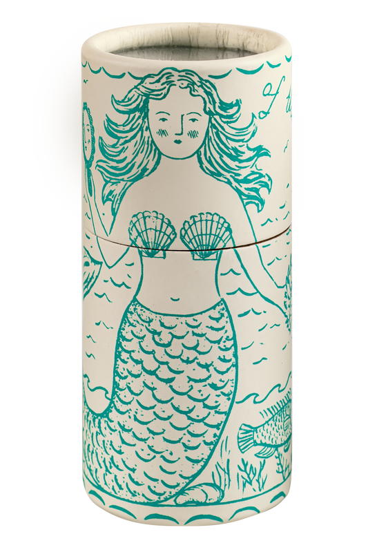 A cylindrical ceramic candle tin featuring a teal mermaid illustration on a warm cream background, with a thin metal wick visible at the top.